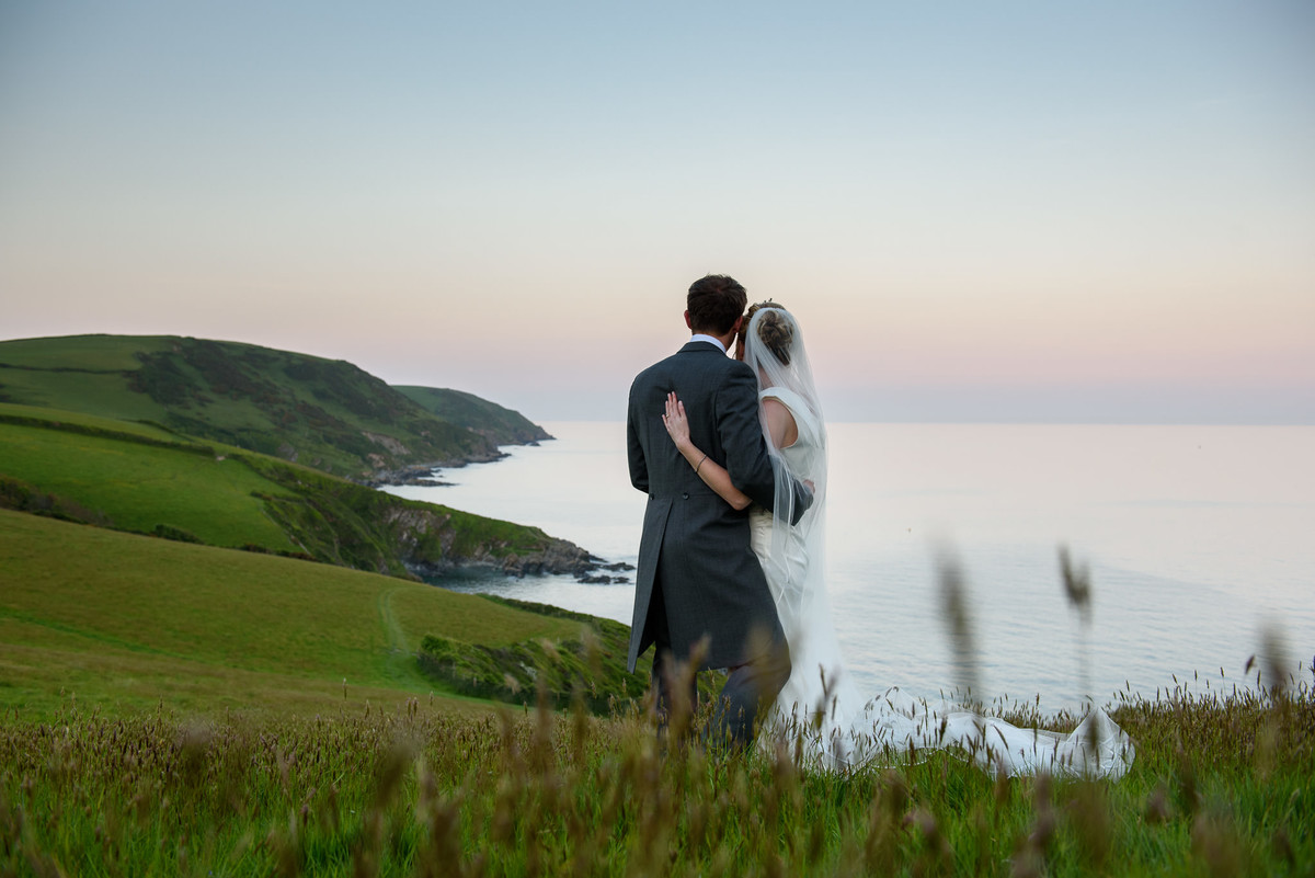 bride and groom in embrace looking at the coastline views